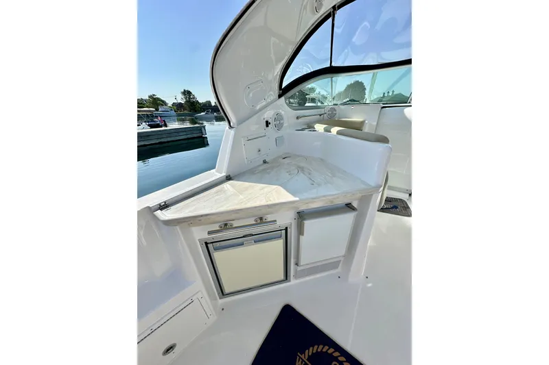 Slide: The Image of 2015 Rinker 340 Express Cruiser interior with kitchenette and seating, docked by the water. - 6