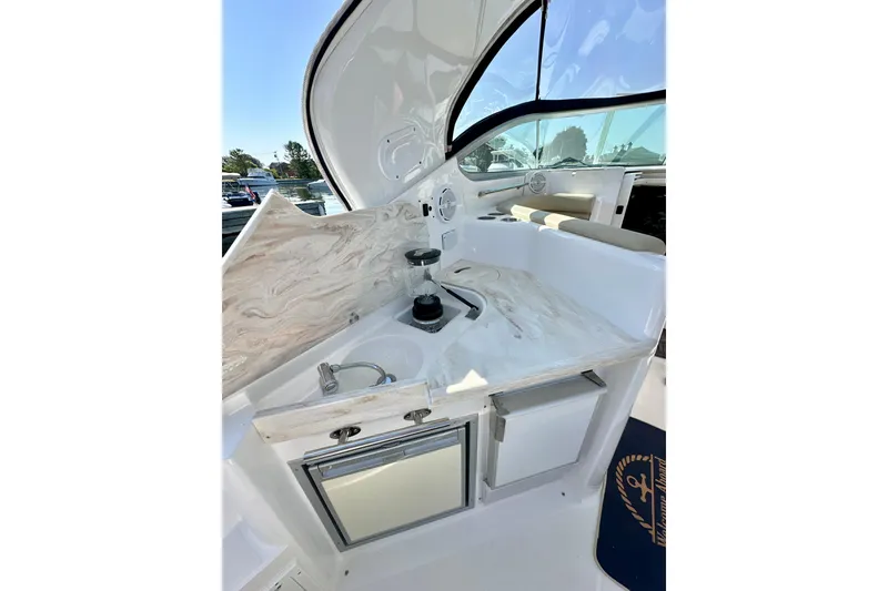 Slide: The Image of 2015 Rinker 340 Express Cruiser interior with kitchenette, featuring sink and storage cabinets. - 7