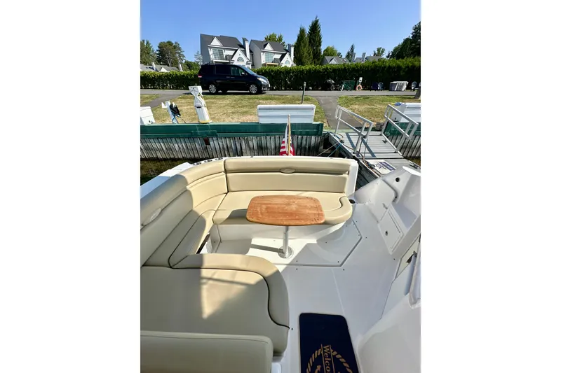 Slide: The Image of 2015 Rinker 340 Express Cruiser with beige seating and wooden table, docked near a house. - 8