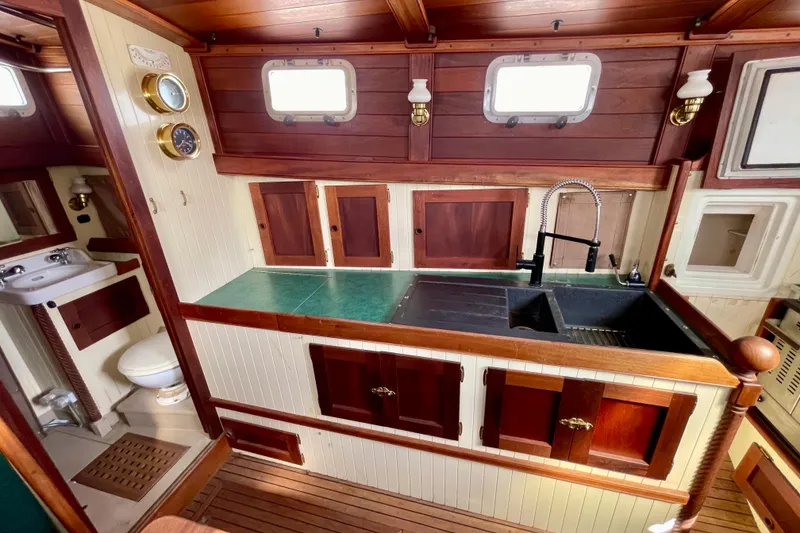 Slide: The Image of Wooden boat interior with vintage kitchen and bathroom, featuring brass fixtures and porthole windows. - 19