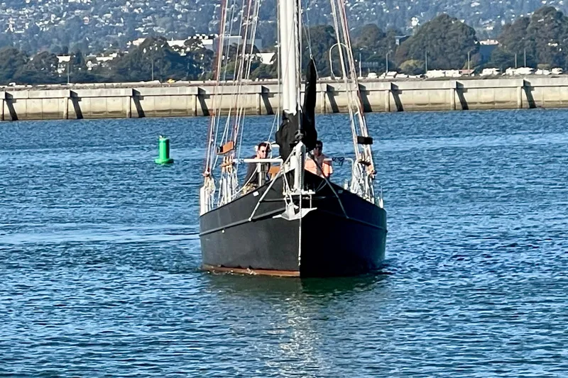 Slide: The Image of Sailboat "Pinky Custom 2008" navigating calm waters near a coastal city. - 3