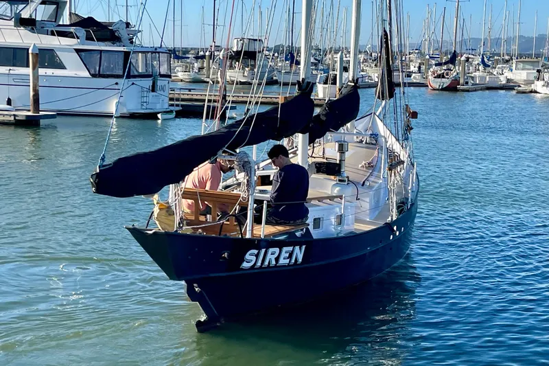Slide: The Image of Sailboat "Siren" by Pinky Custom, 2008, docked in a marina with two people aboard. - 8