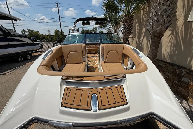 Slide: The Image of 2019 MasterCraft X24 boat with tan seating and teak accents, parked outdoors. - 3