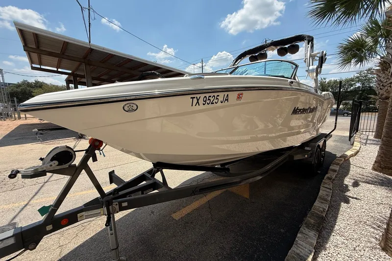 Slide: The Image of 2019 MasterCraft X24 boat on trailer, parked outdoors under sunny sky. - 4