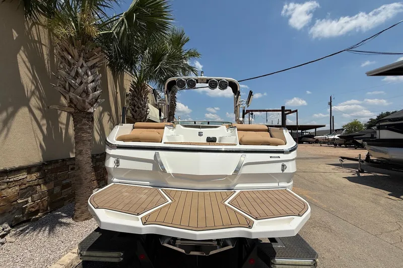 Slide: The Image of 2019 MasterCraft X24 boat with teak deck, parked under palm trees. - 6