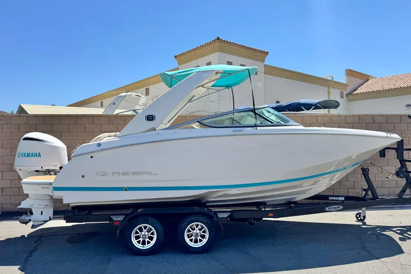 Slide: The Image of 2018 Regal 23 OBX boat on trailer, featuring Yamaha outboard motor, parked outdoors. - 0