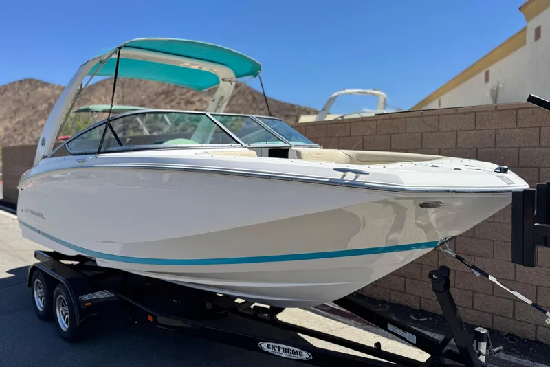 Slide: The Image of 2018 Regal 23 OBX boat on trailer, white with teal accents, parked outdoors. - 1
