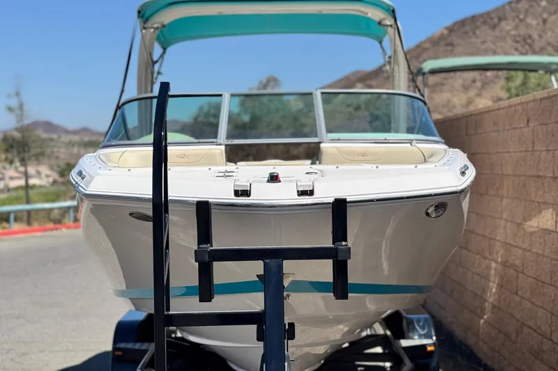 Slide: The Image of 2018 Regal 23 OBX boat on trailer, parked near a stone wall, with mountains in background. - 2