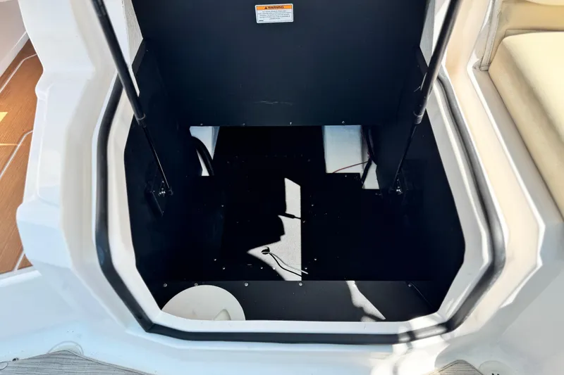 Slide: The Image of Storage compartment in 2018 Regal 23 OBX boat, featuring black interior and hydraulic supports. - 23