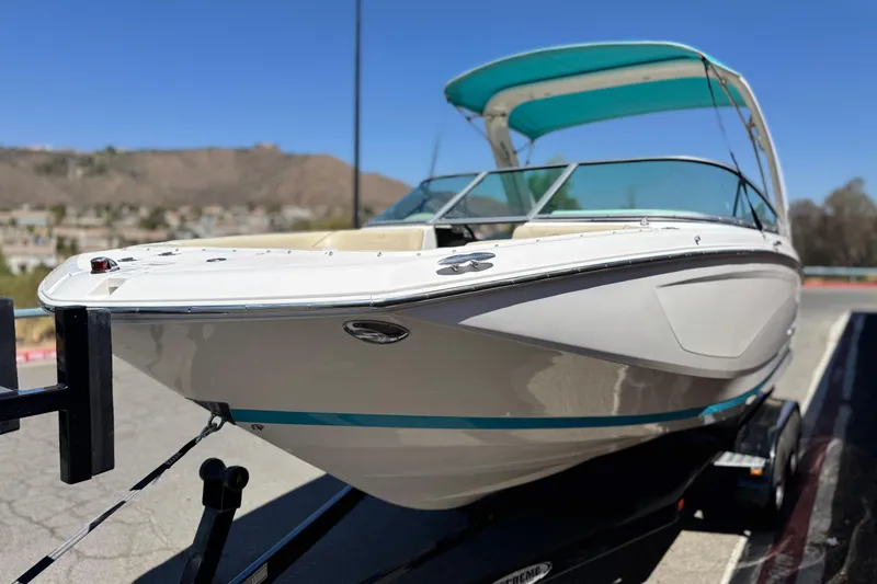 Slide: The Image of 2018 Regal 23 OBX boat on trailer, white with teal accents, sunny day. - 3