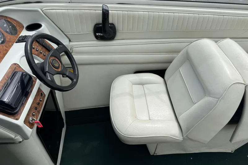 Slide: The Image of Interior of a 1995 Celebrity 220 BR boat with white seating and wood-accented dashboard. - 11