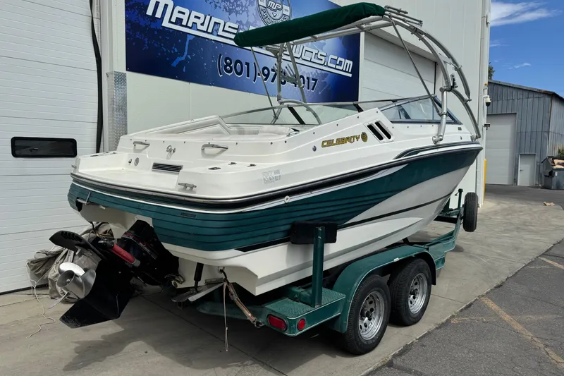 Slide: The Image of 1995 Celebrity 220 BR boat on trailer, parked outside marine service shop. - 4
