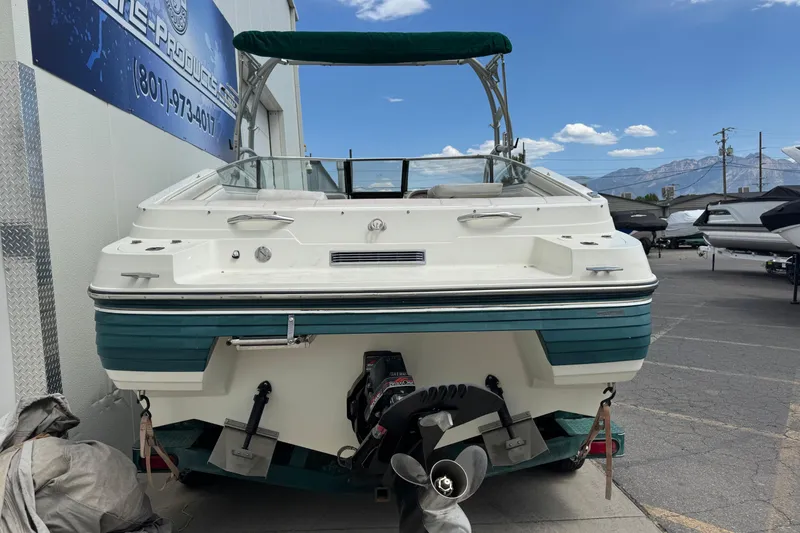 Slide: The Image of 1995 Celebrity 220 BR boat with green accents, parked outdoors under a clear blue sky. - 5