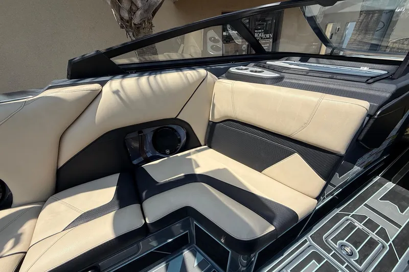 Slide: The Image of 2022 Centurion Ri245 boat interior with beige and black seating, cup holders, and sleek design. - 9