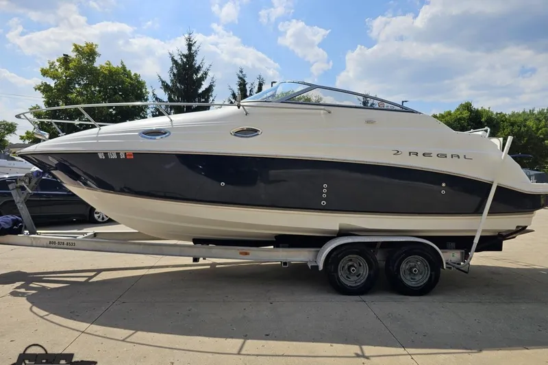 Slide: The Image of 2003 Regal Commodore 2665 boat on trailer, parked outdoors under a sunny sky. - 15