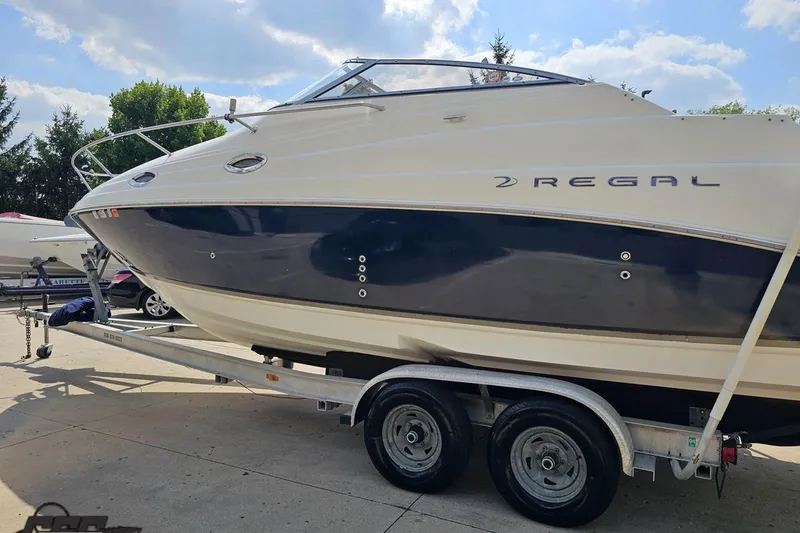 Slide: The Image of 2003 Regal Commodore 2665 boat on trailer under a sunny sky. - 21