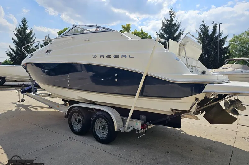 Slide: The Image of 2003 Regal Commodore 2665 boat on trailer, parked outdoors under a blue sky. - 22
