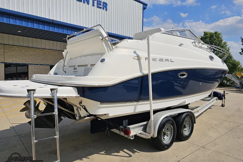 Slide: The Image of 2003 Regal Commodore 2665 boat on trailer, parked outside a building under a clear sky. - 28
