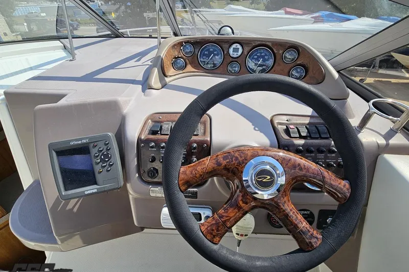 Slide: The Image of 2003 Regal Commodore 2665 boat dashboard with wood-trimmed steering wheel and navigation controls. - 49
