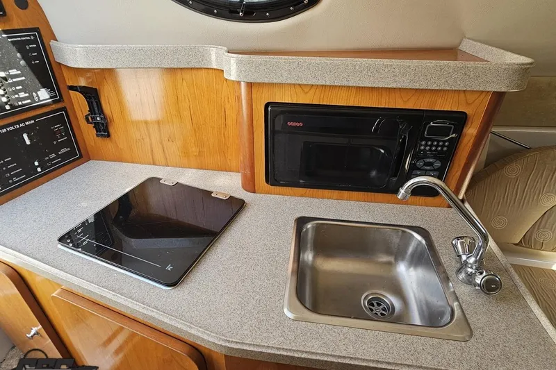 Slide: The Image of 2003 Regal Commodore 2665 boat kitchen with sink, microwave, and stovetop. - 59