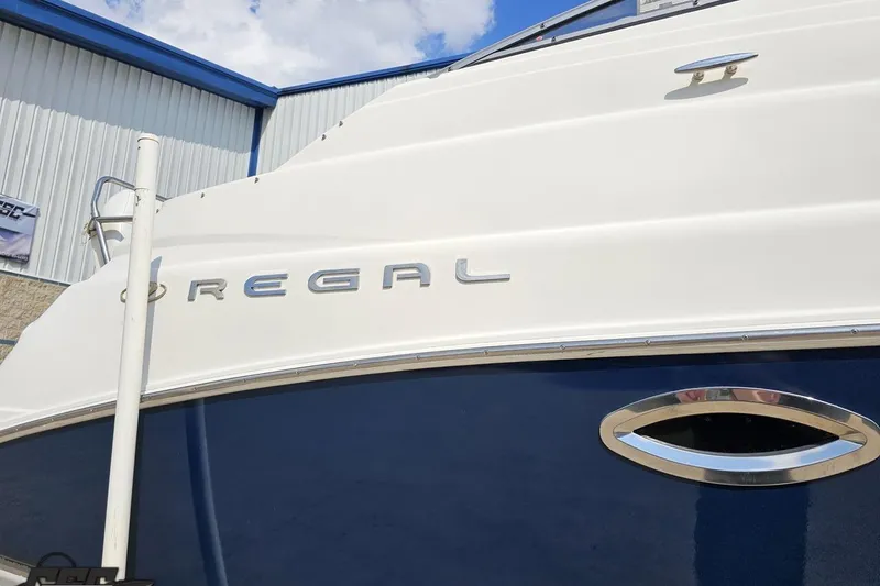 Slide: The Image of 2003 Regal Commodore 2665 boat exterior with logo, white and blue design. - 6