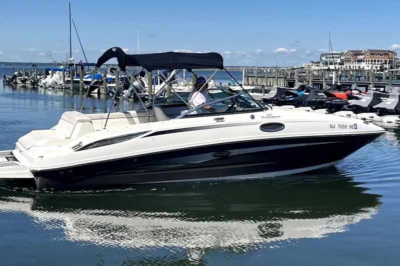 Slide: The Image of 2012 Sea Ray 260 Sundeck boat docked in a marina under clear blue skies. - 2