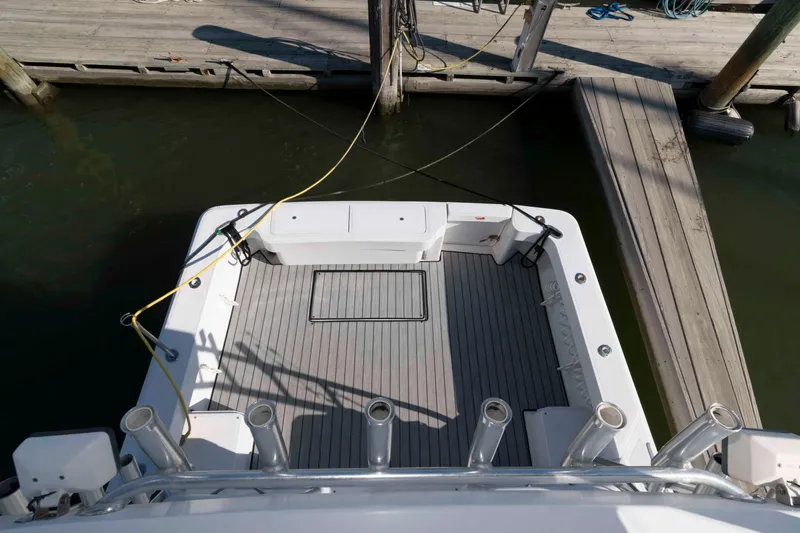 Slide: The Image of 1998 Luhrs 32 Open boat docked, showing spacious deck and fishing rod holders. - 13