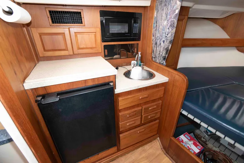 Slide: The Image of 1998 Luhrs 32 Open cabin with kitchenette, featuring sink, microwave, and compact fridge. - 20