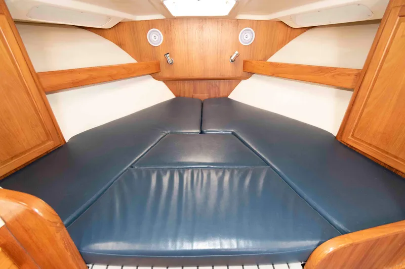 Slide: The Image of 1998 Luhrs 32 Open cabin interior with blue cushioned V-berth and wooden accents. - 21