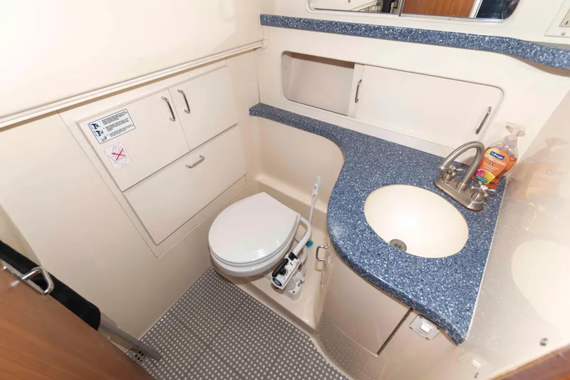 Slide: The Image of 1998 Luhrs 32 Open boat bathroom with sink, toilet, and storage cabinets. - 22