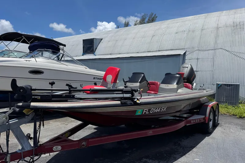 Slide: The Image of 1999 Skeeter ZX 195 boat on trailer, parked outdoors near a larger vessel. - 1