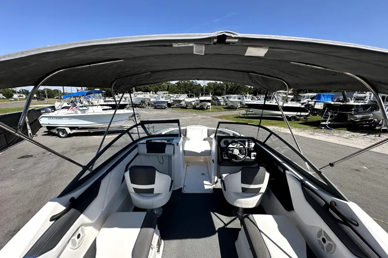 Slide: The Image of 2020 Yamaha Boats SX210 interior with canopy, parked among other boats under a clear blue sky. - 13