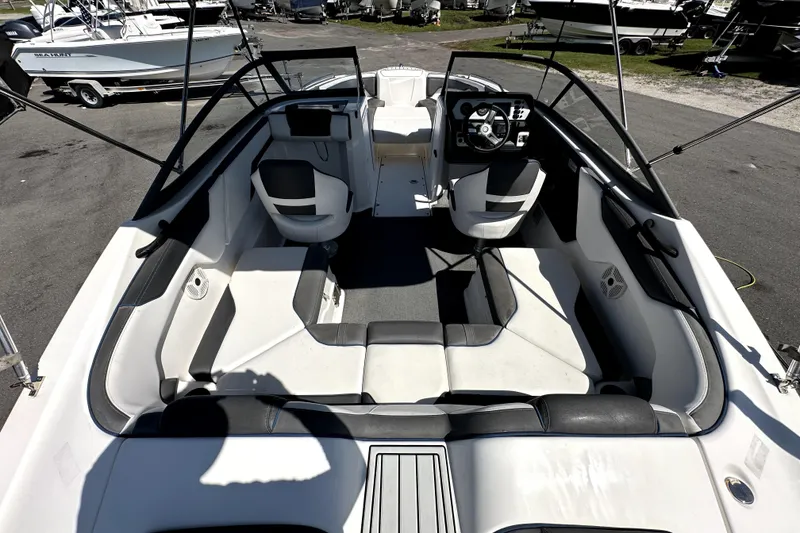 Slide: The Image of 2020 Yamaha Boats SX210 interior with seating and steering wheel, parked among other boats. - 14