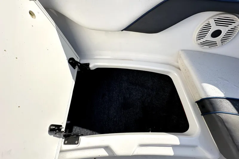Slide: The Image of Open storage compartment on a 2020 Yamaha SX210 boat, featuring speaker and seating area. - 28
