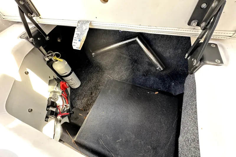 Slide: The Image of 2020 Yamaha Boats SX210 storage compartment with fire extinguisher and metal rods. - 43