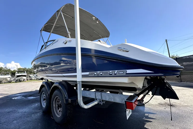 Slide: The Image of 2020 Yamaha Boats SX210 on trailer, blue and white, with canopy under clear sky. - 5