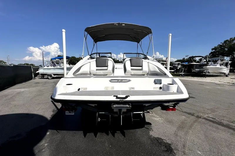 Slide: The Image of 2020 Yamaha Boats SX210, rear view, parked on asphalt under clear blue sky. - 6