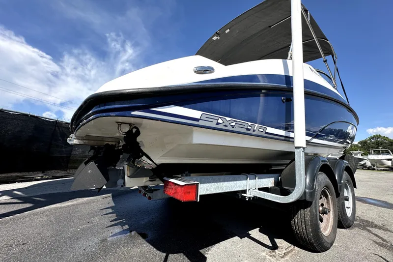 Slide: The Image of 2020 Yamaha Boats SX210 on trailer, blue and white design, sunny day. - 8