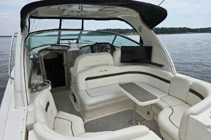 Slide: The Image of 2006 Sea Ray 380 Sundancer yacht interior with white seating and table on calm water. - 6