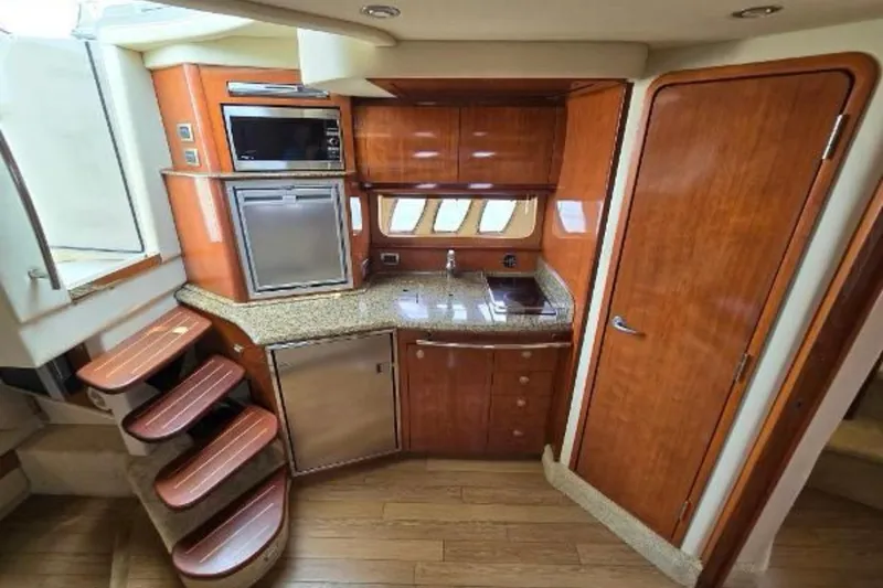 Slide: The Image of 2006 Sea Ray 380 Sundancer interior kitchen with wood cabinetry and modern appliances. - 8
