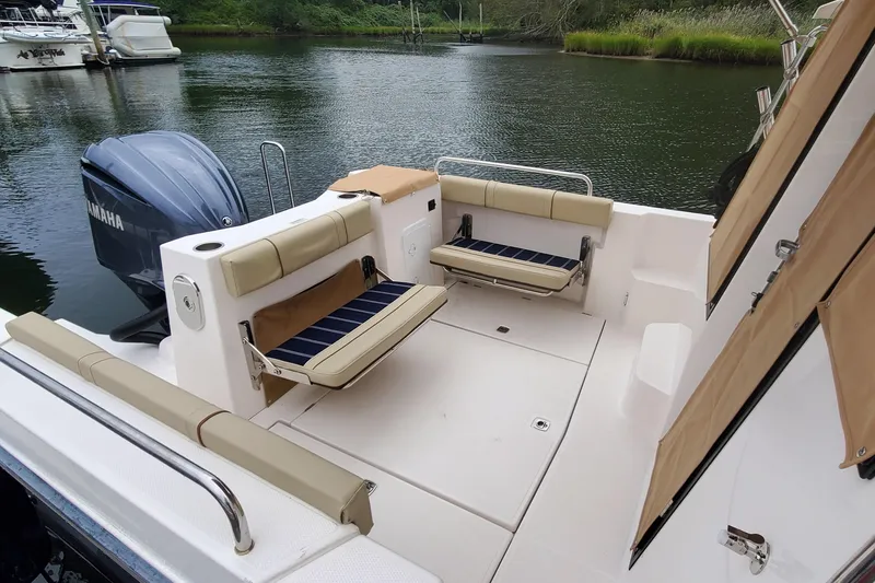 Slide: The Image of 2021 Ranger Tugs R-25 boat interior with seating, Yamaha engine, and scenic water backdrop. - 12