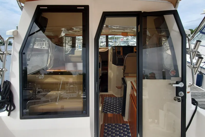 Slide: The Image of 2021 Ranger Tugs R-25 boat interior with open door, showcasing seating and dashboard. - 15