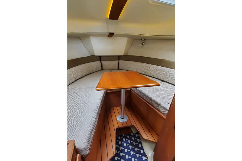 Slide: The Image of 2021 Ranger Tugs R-25 cabin interior with wooden table and cushioned seating. - 21