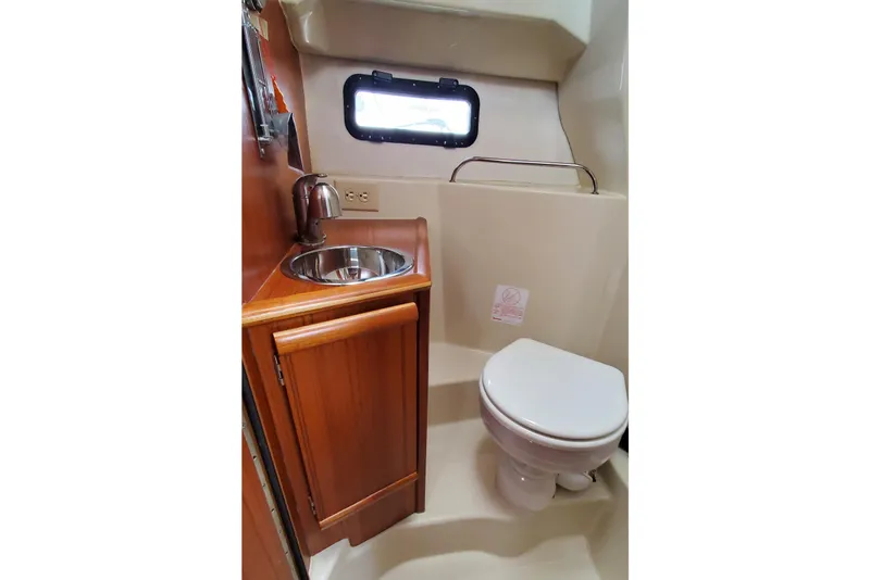 Slide: The Image of 2021 Ranger Tugs R-25 bathroom with sink, toilet, and porthole window. - 22