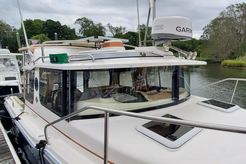 Slide: The Image of 2021 Ranger Tugs R-25 boat docked by a scenic riverside with lush greenery. - 3