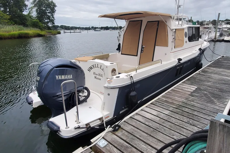 Slide: The Image of 2021 Ranger Tugs R-25 boat docked, featuring Yamaha outboard motor, in a serene marina setting. - 5