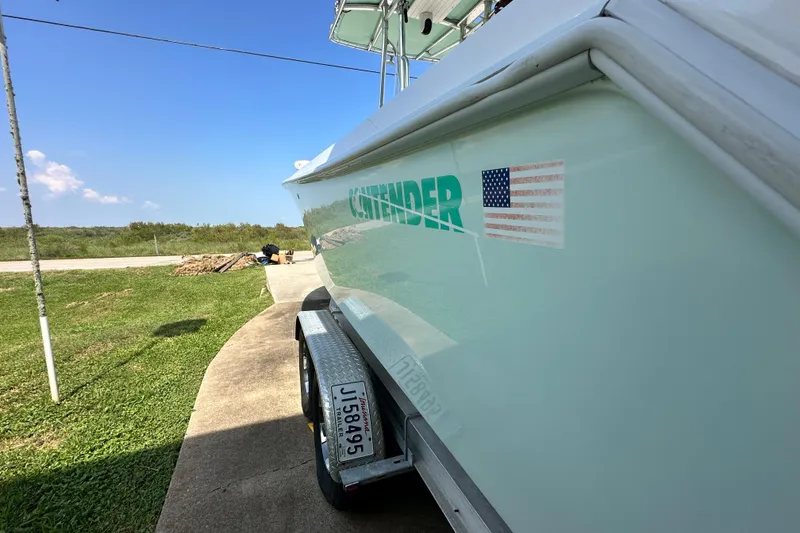 Slide: The Image of 2013 Contender 25 Tournament boat on trailer, American flag decal, sunny day. - 12