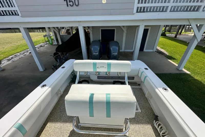 Slide: The Image of 2013 Contender 25 Tournament boat with dual outboard engines, parked under a raised house. - 39