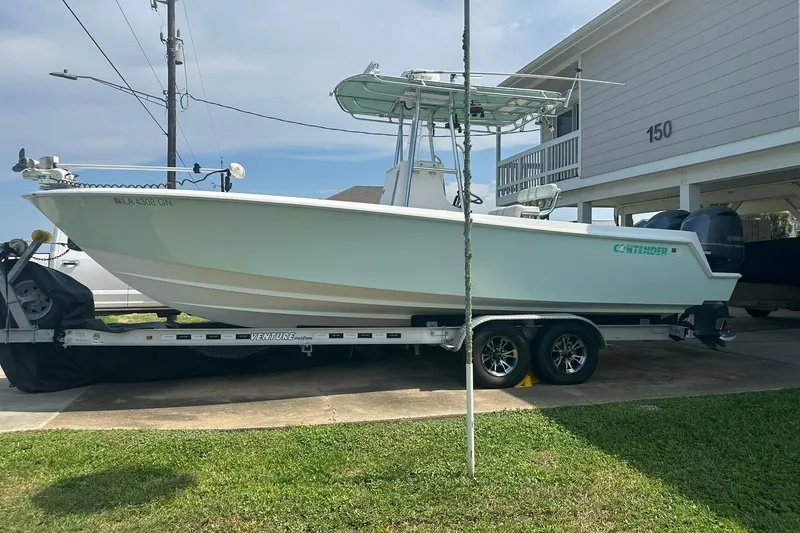 Slide: The Image of 2013 Contender 25 Tournament boat on trailer, parked near a house. - 4