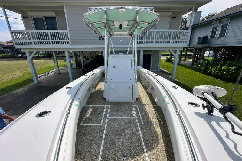 Slide: The Image of 2013 Contender 25 Tournament boat docked near stilt houses, showcasing spacious deck and center console. - 44